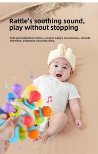 Close-up of baby grasping a colorful Manhattan ball rattle toy on soft bedding