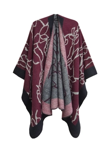 Detail of burgundy knit poncho showing floral patterns and gray reversible inner layer
