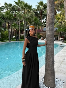 Elegant black one-shoulder evening dress with pleated skirt detail at poolside