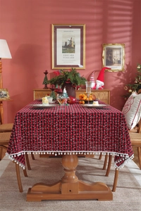 Detail of red and black buffalo plaid Christmas tablecloth with white pom pom lace trim