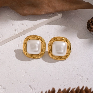 Vintage gold square earrings with white pearl inlay set on a rustic decorative background