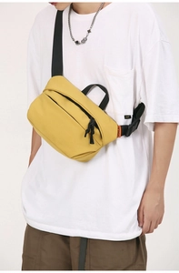 Detail of yellow nylon crossbody bag with durable black strap and brand woven label