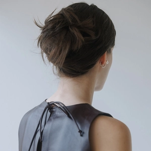 Detail shot of a 18k gold plated brass ear cuff with pearl on a model in leather vest