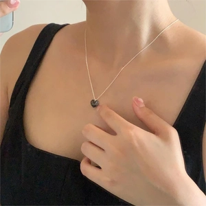 Close-up of heart pendant necklace with dark grey crystal on silver link chain