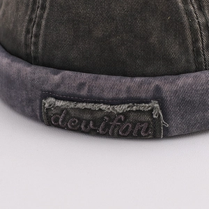 Macro detail of washed denim docker hat with devifon embroidered patch and frayed edges