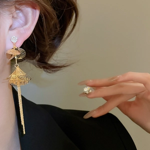 Gros plan de boucles d'oreilles dorées à pompons et pétales de zircon sur un mannequin