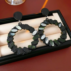 Macro detail of geometric black earrings with mosaic shell inlays in a gift box