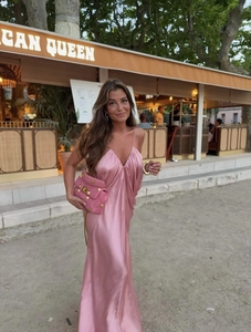 Elegant pink satin V-neck evening dress with studded shoulder bag in chic restaurant setting