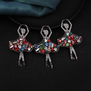 Detailed close-up of three ballerina brooches with colorful rhinestones on silk