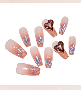 Macro view of gradient pink press-on nails with 3D red heart gems and glitter finish