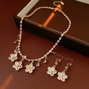 Detailed view of luxury gold zircon flower and water drop necklace and earring set on leather
