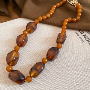 Detail view of amber acrylic irregular beads on a brown vintage necklace set