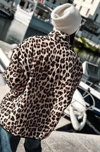 Outdoor back view of a quilted leopard print jacket with a white knit beanie and jeans
