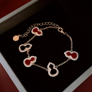 Macro shot of rose gold gourd bracelets with red stones and diamonds in jewelry box