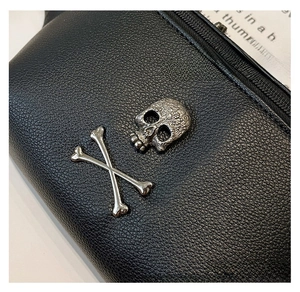 Close-up of black pebble leather chest bag featuring vintage silver skull buckle