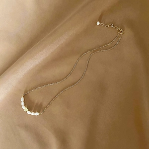 Elegant gold heart freshwater pearl necklace displayed on luxurious satin fabric