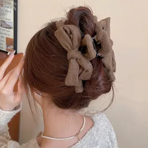 Elegant large brown fabric bow hair claw clip for women shown on back of head