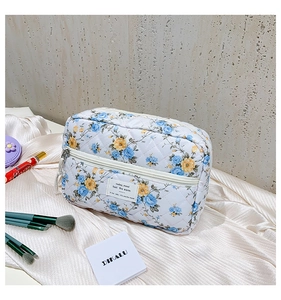 Detail of floral quilted makeup bag featuring blue and yellow flower patterns and text tag
