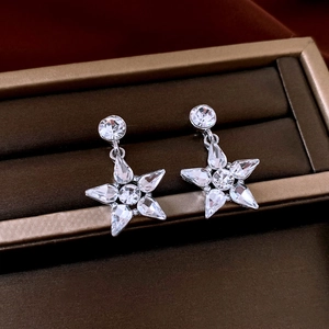 Macro shot of silver star drop earrings featuring sparkling cubic zirconia crystals