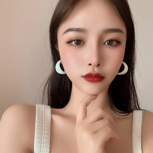 Close-up of a model wearing white C-shaped acrylic hoop earrings for women