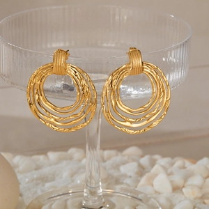Detailed view of layered irregular golden hoop earrings on a glass with white stones