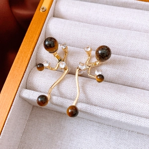 Macro shot of gold-plated tiger eye drop earrings with micro-set zircon stones
