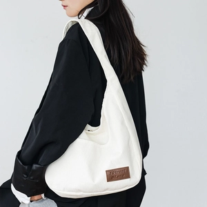 Minimalist white corduroy tote bag shown on model with spacious shoulder strap design