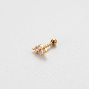 Close-up of golden cartilage stud earring with four marquise-cut clear zircons on white