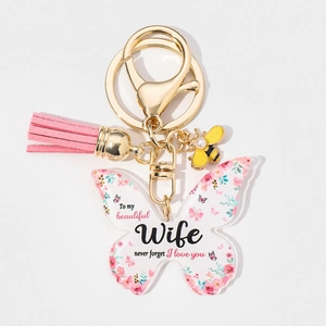 Detail of acrylic butterfly keychain with floral wife message, pink tassel and bee charm