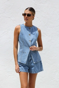 Détail d'un gilet en jean sans manches bleu clair boutonné et d'un short large assorti