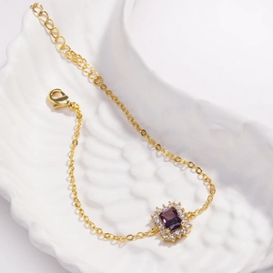 Détail d'un élégant bracelet en or avec une pierre précieuse violette sur un plat en céramique