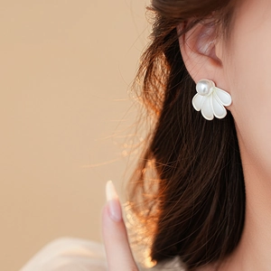 Close-up of model wearing a white petal pearl earring with warm backlight