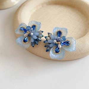 Macro de boucles d'oreilles fleurs bleues avec perles et cristaux sur plateau