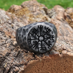 Macro shot of vintage silver Viking compass ring on rustic tree bark background