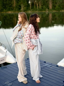 Détail du pull jacquard à motif voilier et du pantalon rayé sur un quai extérieur