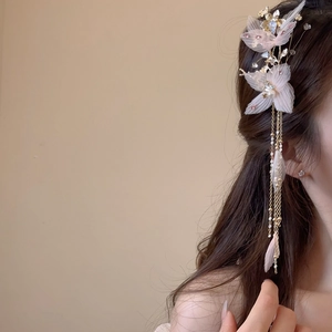 Détail d'une pince à fleurs en tissu rose avec strass brillants et longs glands dorés