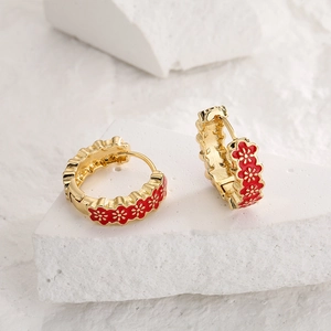 Gold plated hoop earrings with red enamel flower patterns on white stone background