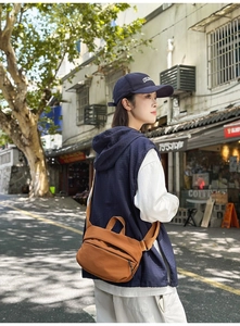 Detail view of caramel nylon crossbody bag with wide shoulder strap on a model outdoors