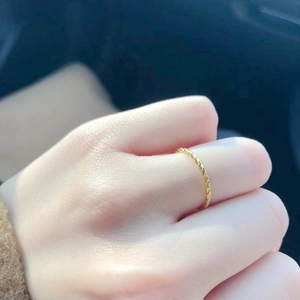 Close-up of twisted rope titanium steel ring in gold finish worn on finger