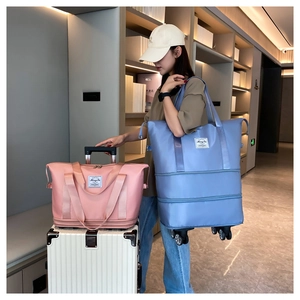 Pink and blue expandable travel bags with wheels shown by a model in an indoor setting