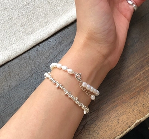 Detailed shot of 925 silver beaded bracelet and white baroque pearl jewelry on hand