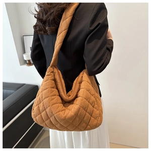 Detail view of the brown quilted corduroy tote bag showing texture on a female model