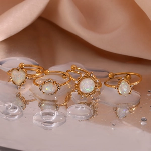 Macro view of gold-plated rings with white opals and rhinestones on silk surface