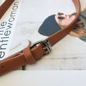 Detailed close-up of brown faux leather strap with silver buckle on fashion magazine