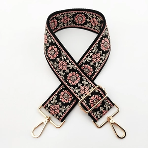 Close-up of bohemian embroidered bag strap with floral patterns and gold metal buckles
