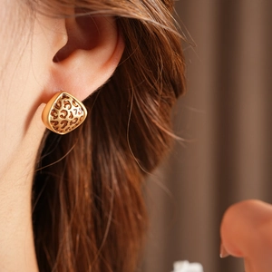 Gros plan d'une boucle d'oreille cœur dorée à motif léopard portée par un mannequin chic
