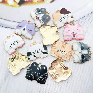 Macro shot of colorful enamel cat charms and golden metal backs for jewelry making