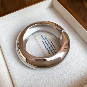 Macro view of polished silver metal bangle with hinge in a wooden jewelry box