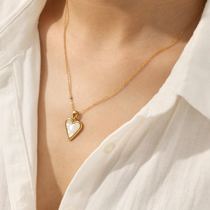 Golden stainless steel heart necklace with white shell inlay worn by a model