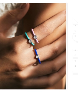Detailed view of model wearing three colorful enamel heart rings with sparkling crystals